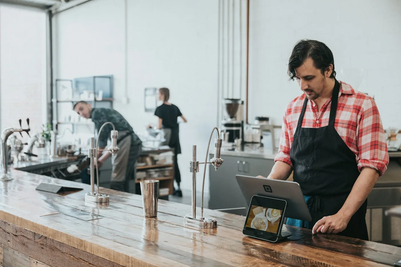 A barista taking an order on a tablet point of sale at a cafe counter