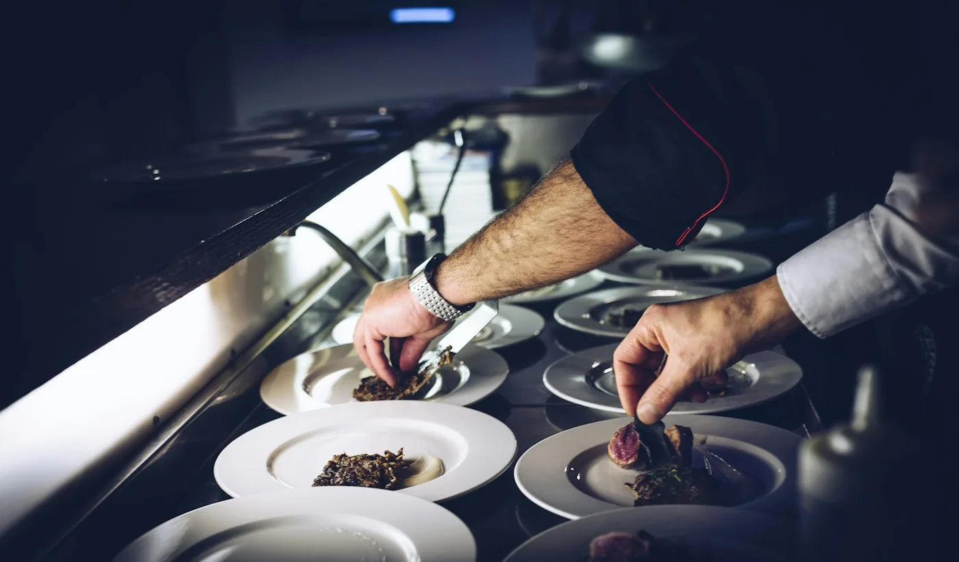 A chef plating a dish in a busy restaurant kitchen